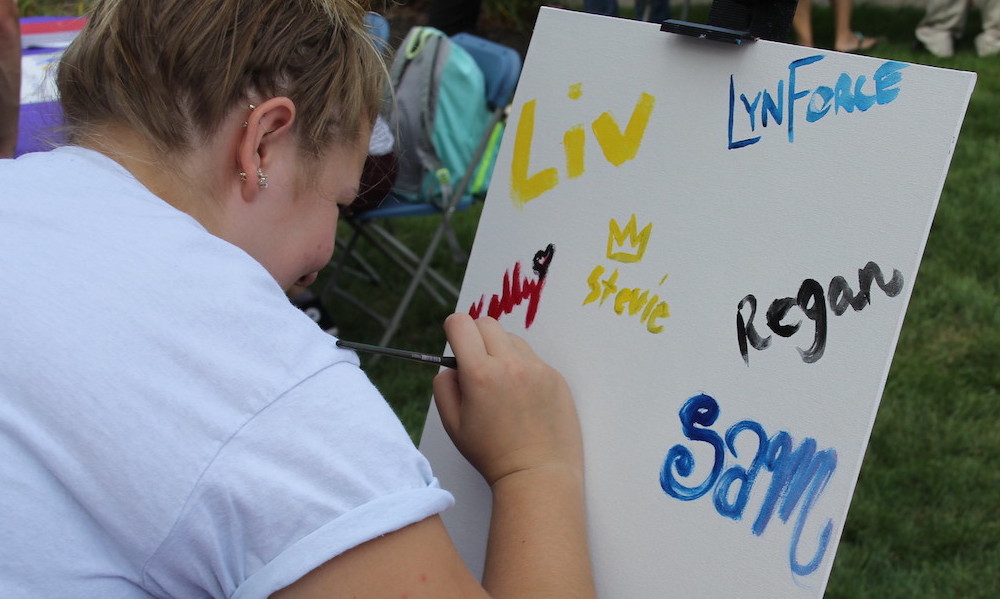 Student paints a sign for art club on Fenner Quadrangle