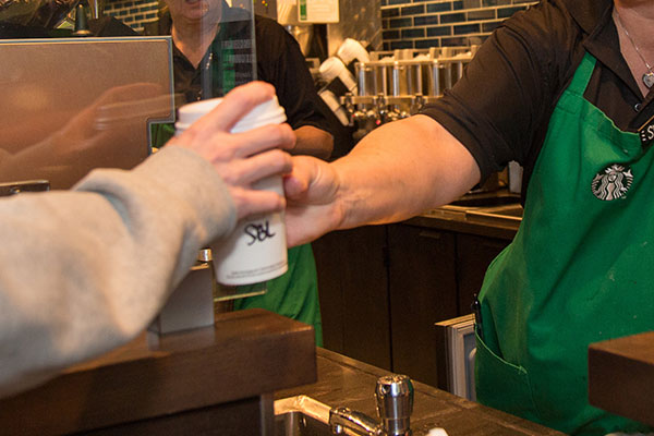 Starbucks barista hands customer a drink