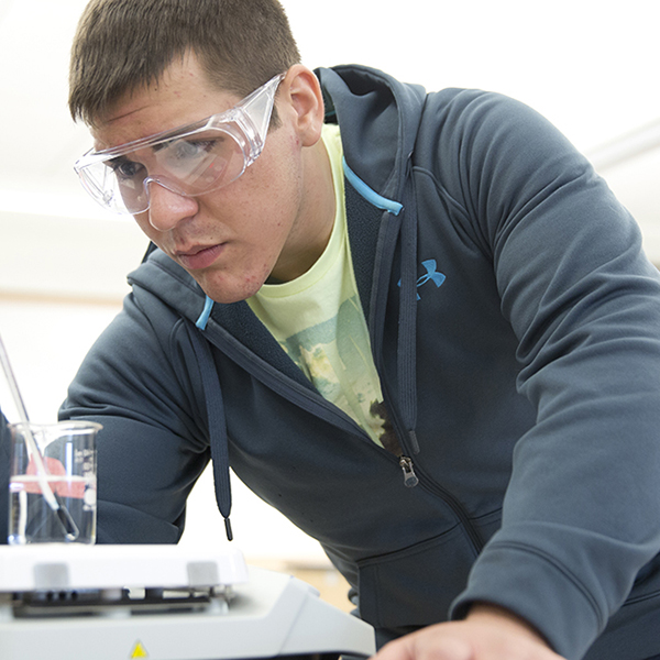 a male student performing a chemistry experiment in a lab