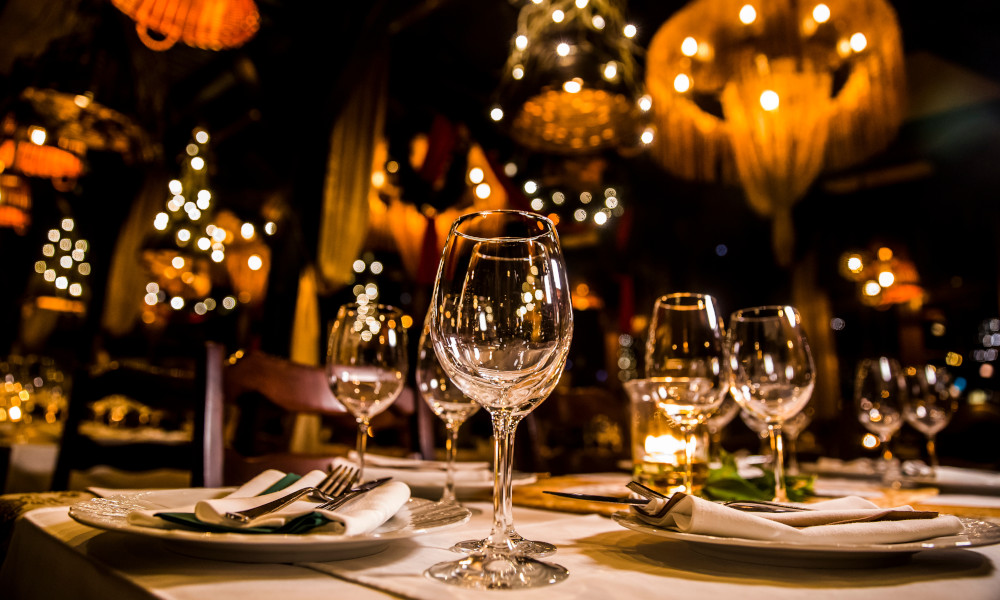 Table at restaurant with wine glasses, plates and silverwear set.