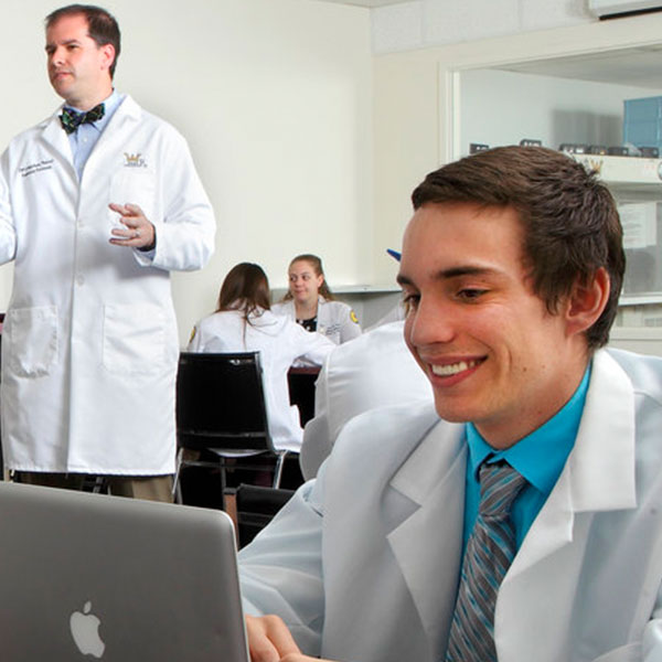 Students wearing white coats in pharmacy classroom